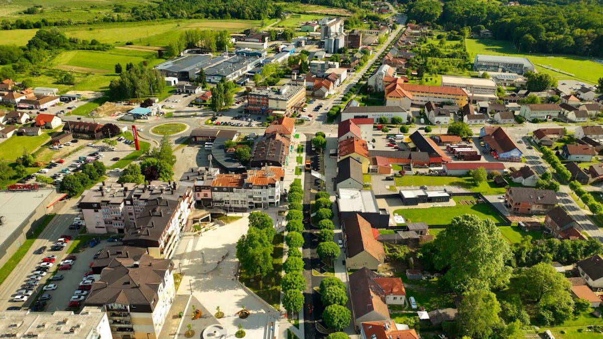 Vibrant aerial view of Garešnica with lush greenery and urban architecture under a clear summer sky.