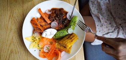 Colorful vegetarian meal with avocado, beans, and corn served on a wooden table. Ideal for healthy lifestyle visuals.