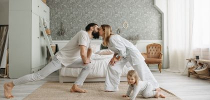 A family enjoying playful bonding moments in a stylish, minimalistic bedroom setting.